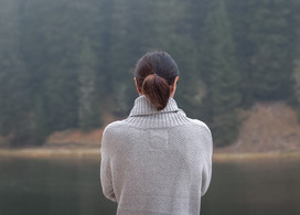 Eine Frau blickt über einen See in den Wald